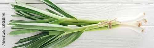 top view of fresh green leek on white wooden table, panoramic shot