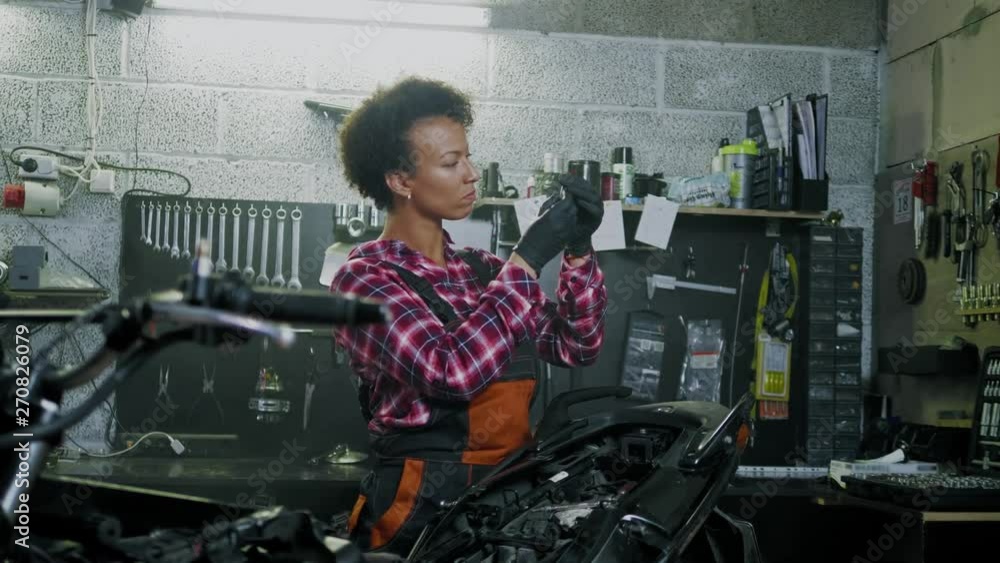 African american woman mechanic repairing a motorcycle in a workshop African american woman mechanic repairing a motorcycle in a workshop