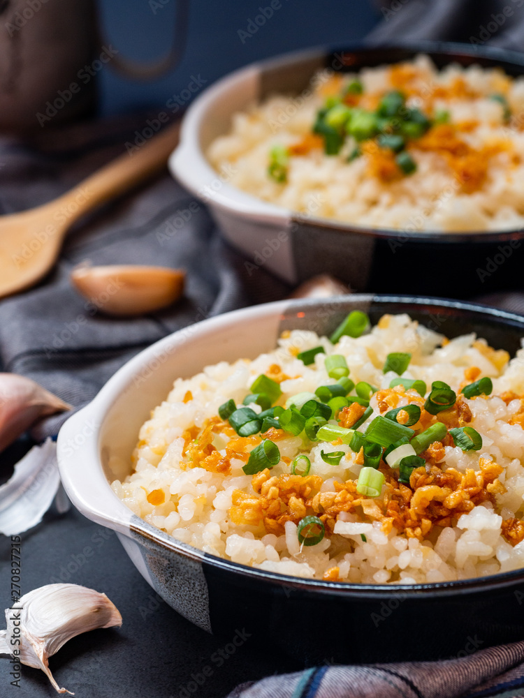 Garlic fried rice in ceramic plate with wood spoon on black background. Garlic fried rice in ceramic plate with wood spoon on black background.