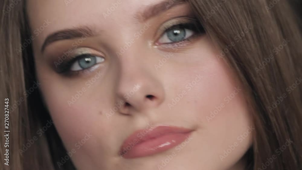 Closeup portrait of young beautiful brown haired woman with blue eyes adorable smile with natural makeup having fun in her room indoors looking at camera and aside. Natural tenderness and femininity Closeup portrait of young beautiful brown haired woman with blue eyes adorable smile with natural makeup having fun in her room indoors looking at camera and aside. Natural tenderness and femininity