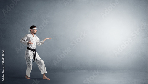 Small karate man fighting in an empty grey copy space