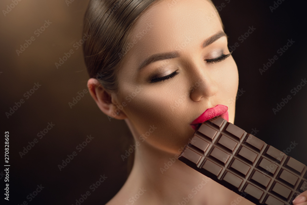 Beautiful young woman eating dark chocolate. Beauty model girl enjoying ...