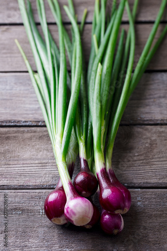 Red onion with fresh green sprouts on wooden background.
