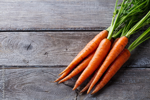 Fresh carrots bunch on a grey wooden background. Copy space. Top view.