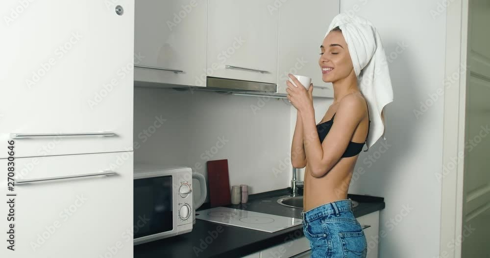Sexy young woman dressed in black bra and white towel drinking coffee in the kitchen Sexy young woman dressed in black bra and white towel drinking coffee in the kitchen