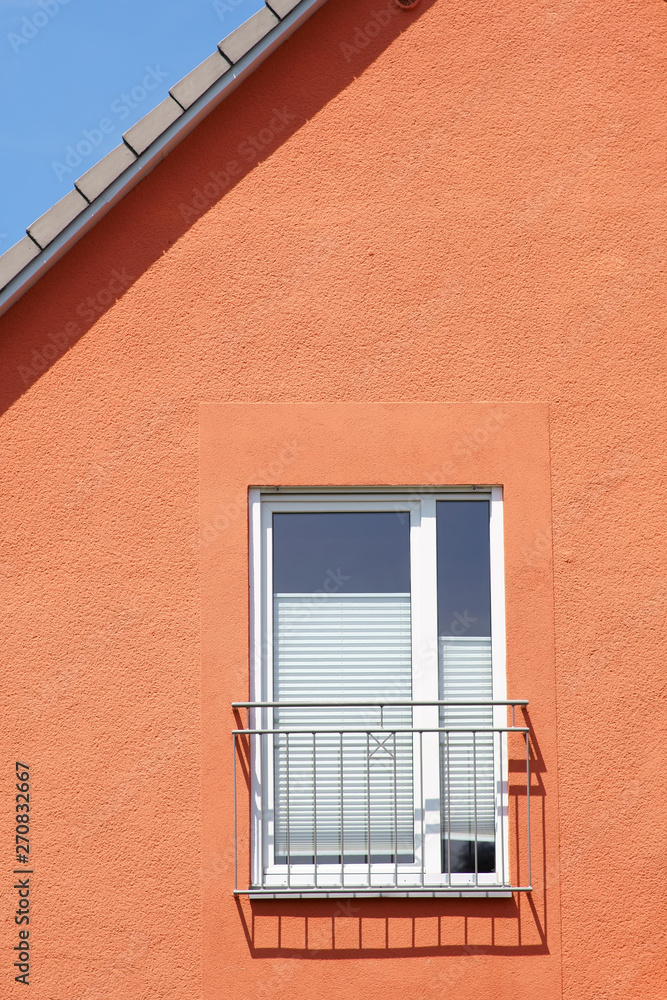 Die Dachkante sowie ein Fenstergeländer eines Wohnhauses werfen Schatten. ..