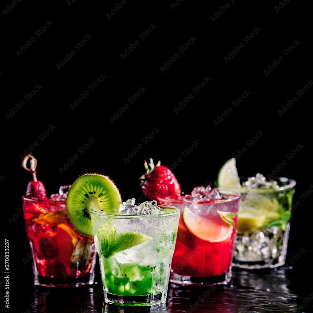 Four colorful tasty alcoholic cocktails in a row at the bar stand. Luxury vacation concept. Isolated on black Four colorful tasty alcoholic cocktails in a row at the bar stand. Luxury vacation concept. Isolated on black