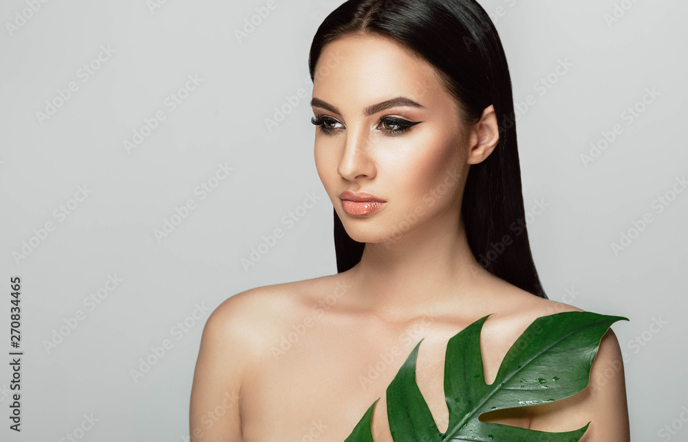 Beautiful woman face with perfect makeup and healthy skin with tropical leaf. beauty face care Beautiful woman face with perfect makeup and healthy skin with tropical leaf. beauty face care