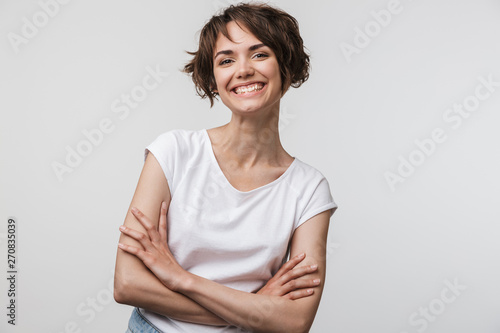 Image of cheerful woman in basic t-shirt smiling at camera while standing with arms crossed