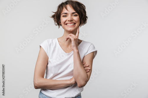 Image of brunette woman in basic t-shirt smiling at camera while standing with arms crossed