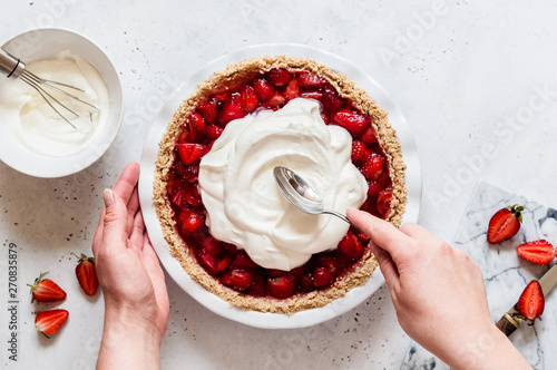 Female Spreading Cream Over a Strawberry Pie