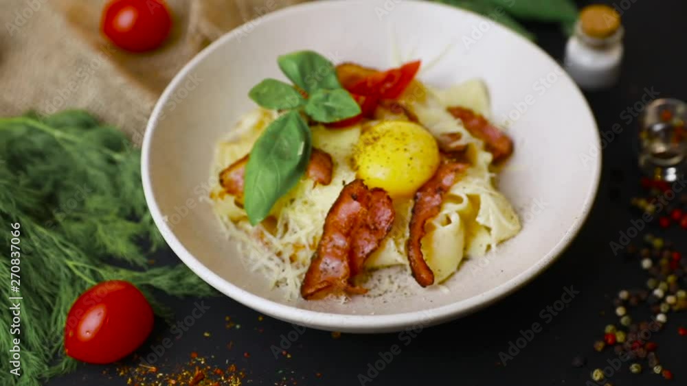 Bacon pasta egg - Italian Carbonara in a plate with raw egg top view. Black background . Slow-mo Bacon pasta egg - Italian Carbonara in a plate with raw egg top view. Black background . Slow-mo