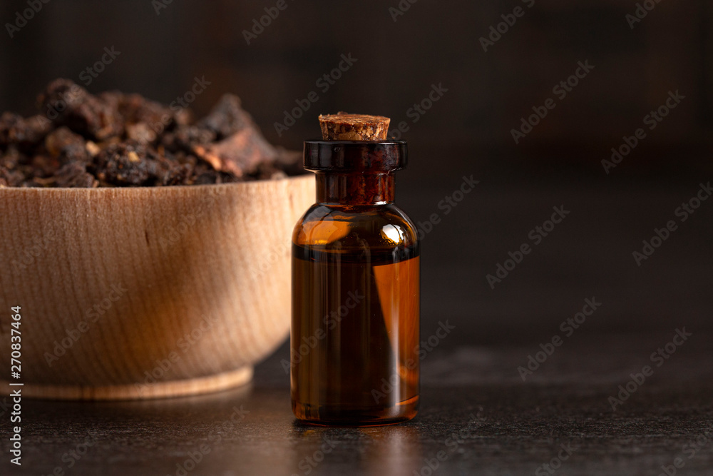 Bowl of Myrrh on a Dark Wood Table with a Bottle of Essential Oil Bowl of Myrrh on a Dark Wood Table with a Bottle of Essential Oil