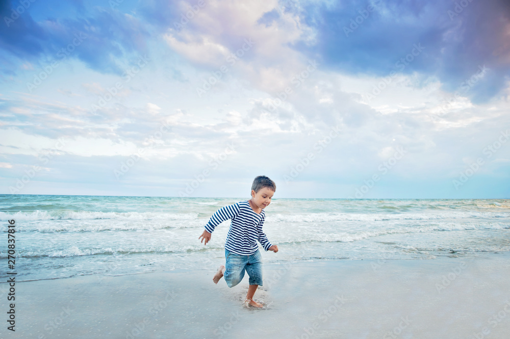 Child running on the beach. Summer vacation. happy kid playing on beach at the sunset time Child running on the beach. Summer vacation. happy kid playing on beach at the sunset time
