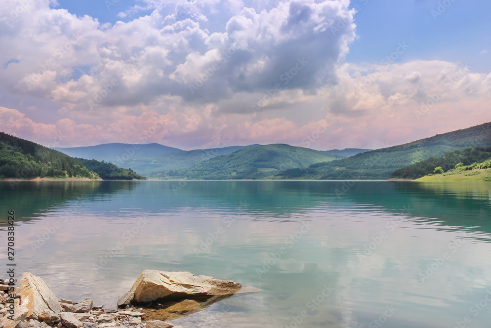 Dramatic, magenta clouds and their reflection in crystal clear lake Zavoj on Old mountain nature park