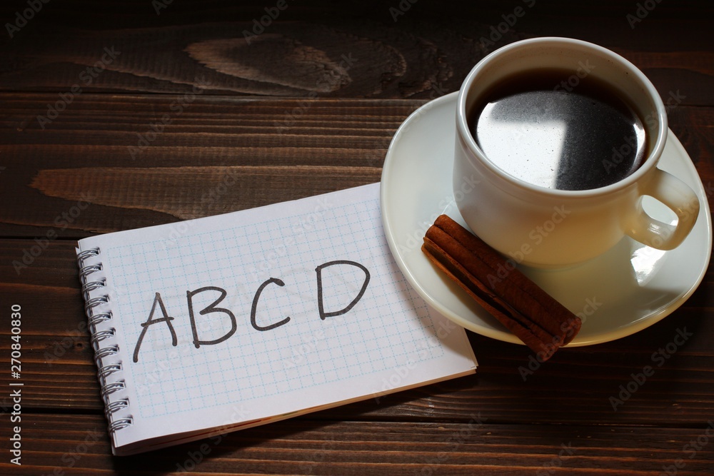 ABCD inscription and word in a notebook near a cup of coffee Stock