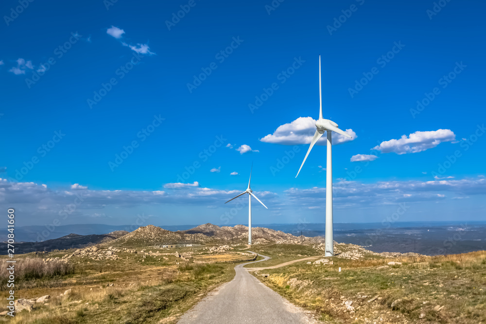 View of a mountains landscape with road and wind turbines on top View of a mountains landscape with road and wind turbines on top