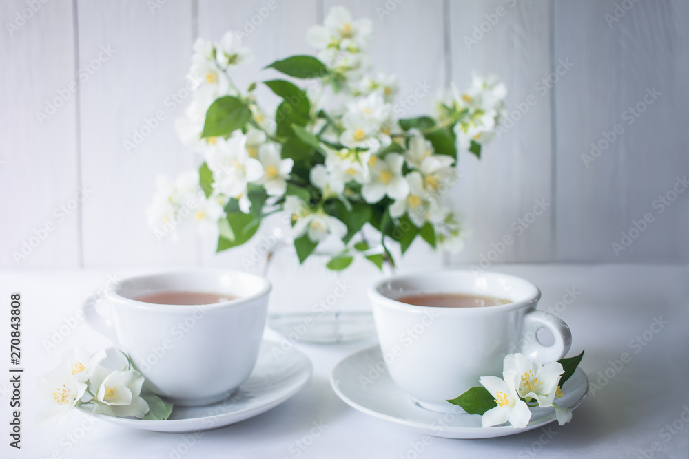 cups of herbal tea and a bouquet of Jasmine on the table. background with cups of tea and Jasmine flowers. cups of herbal tea and a bouquet of Jasmine on the table. background with cups of tea and Jasmine flowers.