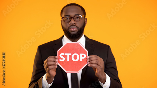 Black man in formal suit showing stop sign, antiracism campaign, social equality photo