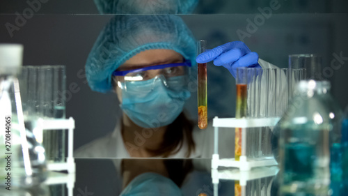Lab worker looking at meat sample in test tube, observing reaction, nutritiology
