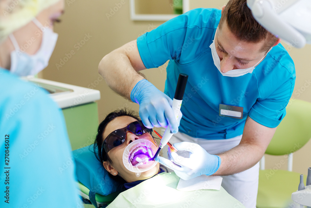 Dentist at work in dental unit with a nurse and a woman lying patient. Dentist at work in dental unit with a nurse and a woman lying patient.