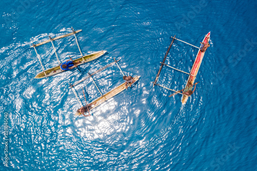 Konstfotografi Boys paddle their outrigger canoes in the warm, blue waters of the Pacific Ocean near remote islands in Papua New Guinea