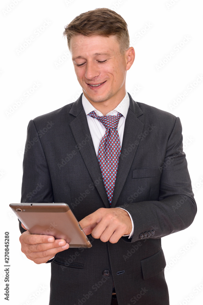 Studio shot of young happy Caucasian businessman using digital t Studio shot of young happy Caucasian businessman using digital t