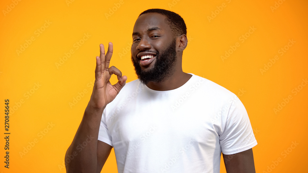 Handsome Afro-American man showing OK sign, customer review, friendly service Handsome Afro-American man showing OK sign, customer review, friendly service
