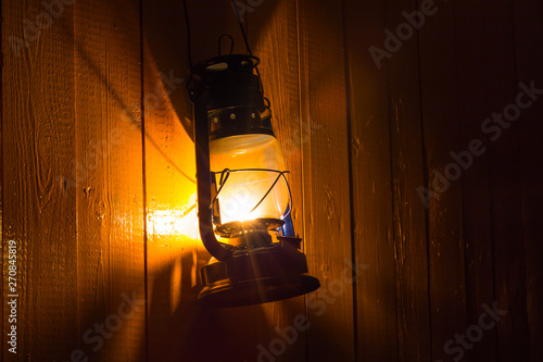old kerosene lantern hanging on the yellow wooden wall