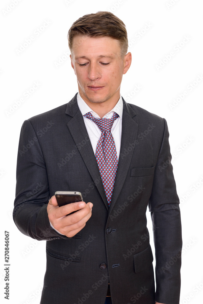 Studio shot of young handsome Caucasian businessman holding mobi