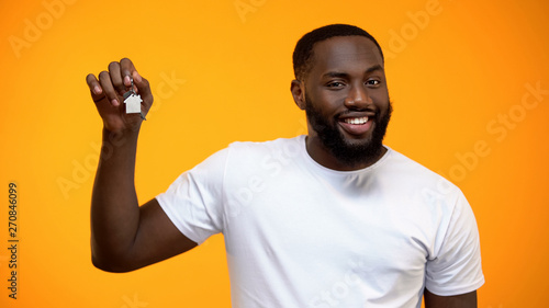 Happy African-American man holding house keys, real estate purchase, mortgage