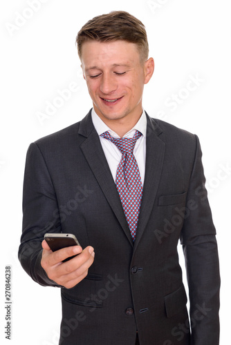 Studio shot of young happy Caucasian businessman holding mobile 
