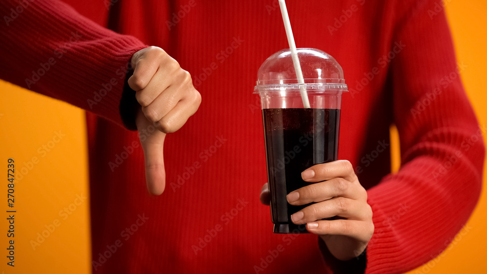 Woman with soft drink glass showing thumbs down, sweet beverage ...