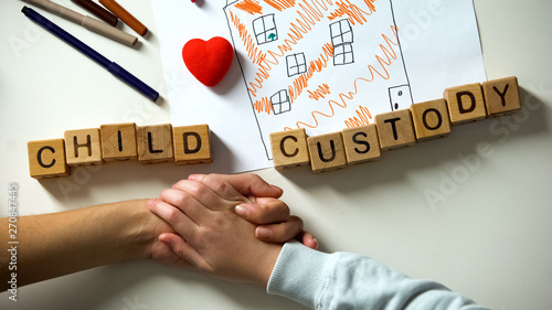 Child custody phrase and toy heart on house picture, kid holding mother hand