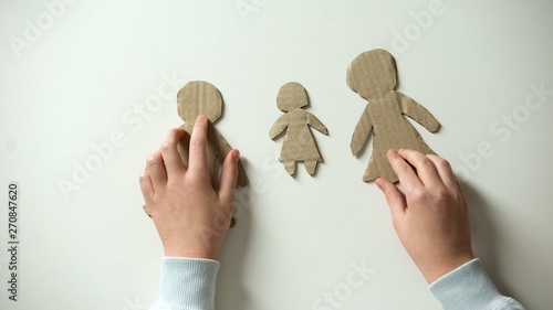 Child putting paper family on white background, orphan needs home, adoption photo