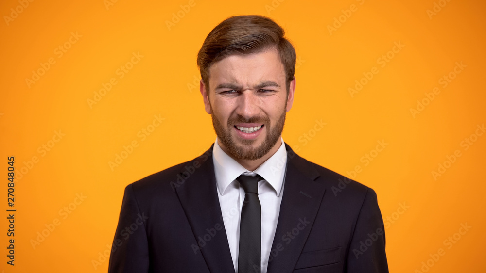 Man in suit grimacing in pain, feeling strong head or stomachache, stressful job Man in suit grimacing in pain, feeling strong head or stomachache, stressful job