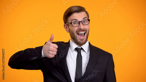 Fotografie Smiling businessman showing thumbs up at camera, making good proposition