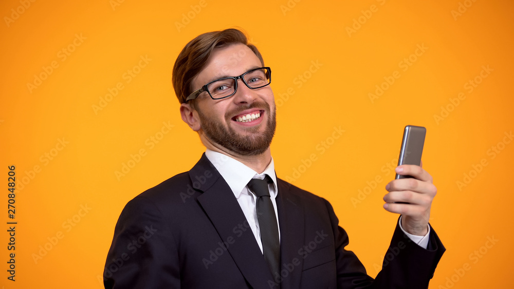Happy man sincerely smiling holding smartphone in hand, favorable crediting, app