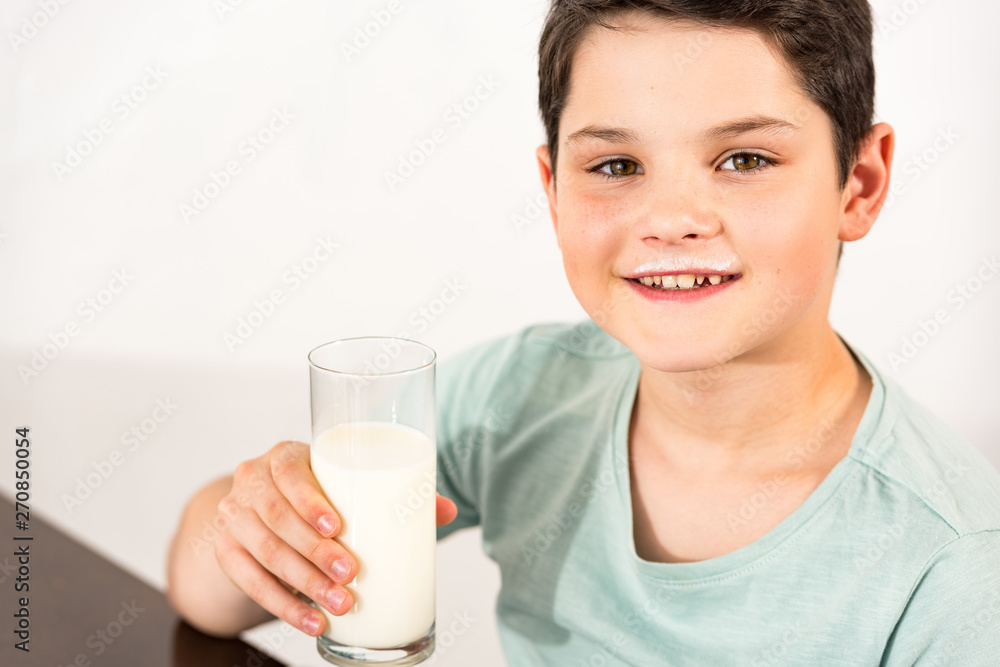 smiling boy holding glass of milk and looking at camera smiling boy holding glass of milk and looking at camera