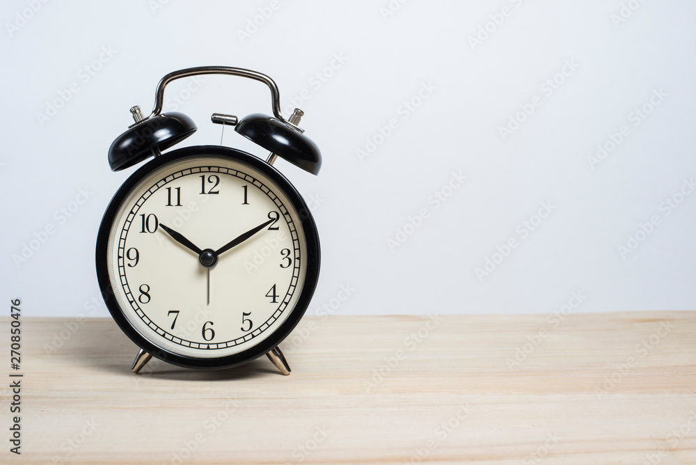 Black old alarm clock on a wooden table on a white background. Deadline. Good morning. Empty space for text Black old alarm clock on a wooden table on a white background. Deadline. Good morning. Empty space for text