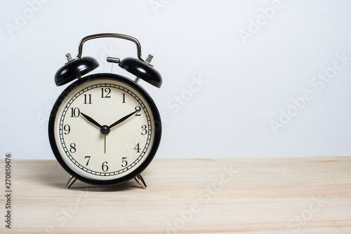 Black old alarm clock on a wooden table on a white background. Deadline. Good morning. Empty space for text