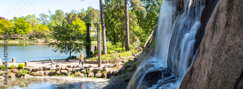 Waterfall with a cliff on the background of the lake and people walk in the park. Sapokka Park in the city of Kotka in Finland. Panoramic photo. photo