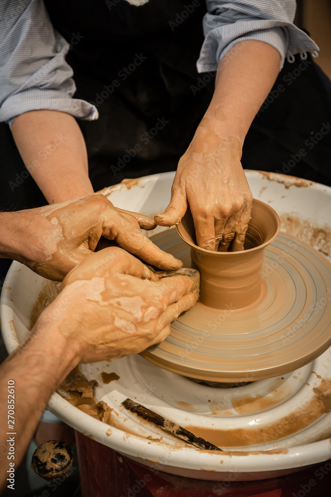 Expert potter teach a woman to work on potter wheel