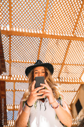 Woman wearing black hat texting on the smart phone in the street