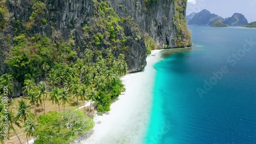 Aerial drone view of pristine tropical white sand beach surrounded by karst rocky cliffs and turquoise sea on Pinagbuyutan Island. El Nido, Palawan, Philippines. Breathtaking landscape photo