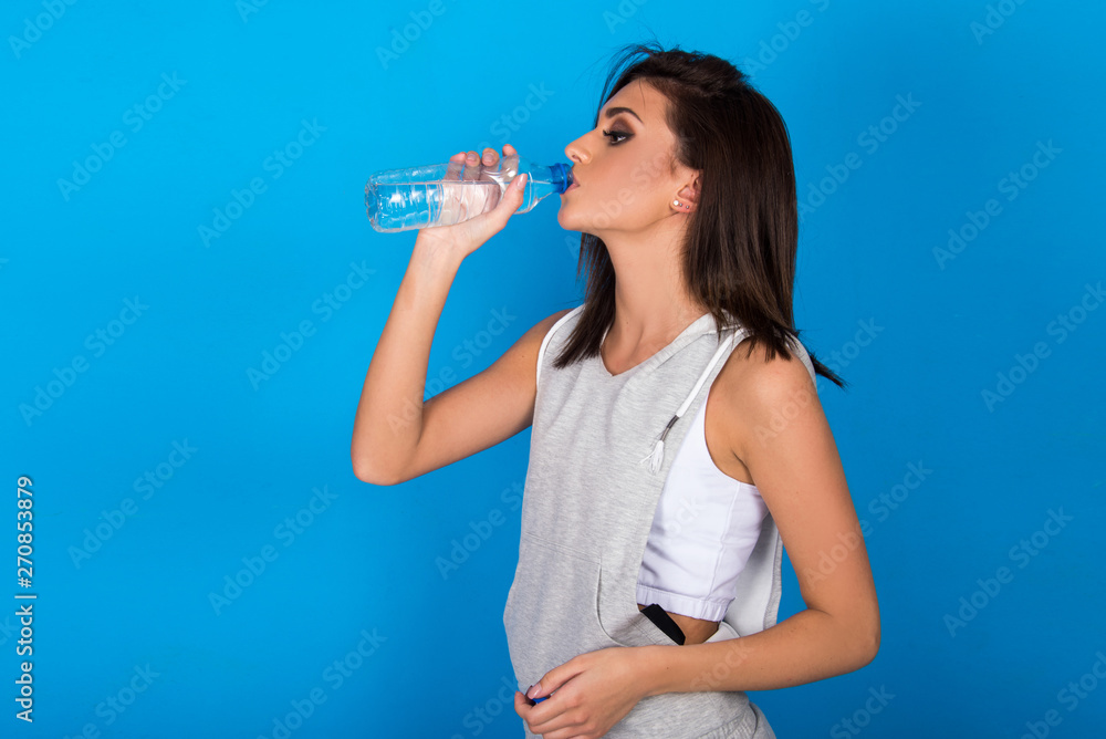Beautiful teen girl holding bottle of water, smiling and drinking fresh water Beautiful teen girl holding bottle of water, smiling and drinking fresh water