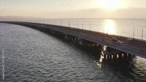 Wallpaper Mural Zooming in aerial view of low water bridge with driving cars across Amur Bay in Vladivostok. Autumn sunset Torontodigital.ca