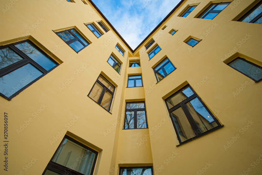 Fototapeta premium Looking up a yellow apartment building.