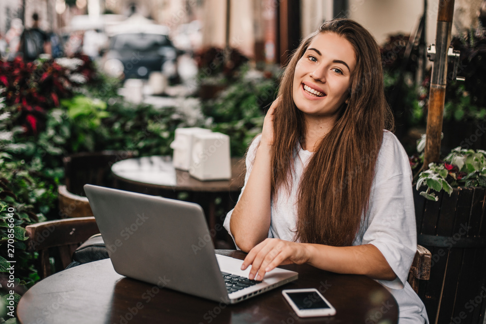 Beautiful woman work on laptop and using phone sitting in street cafe. Beautiful woman work on laptop and using phone sitting in street cafe.