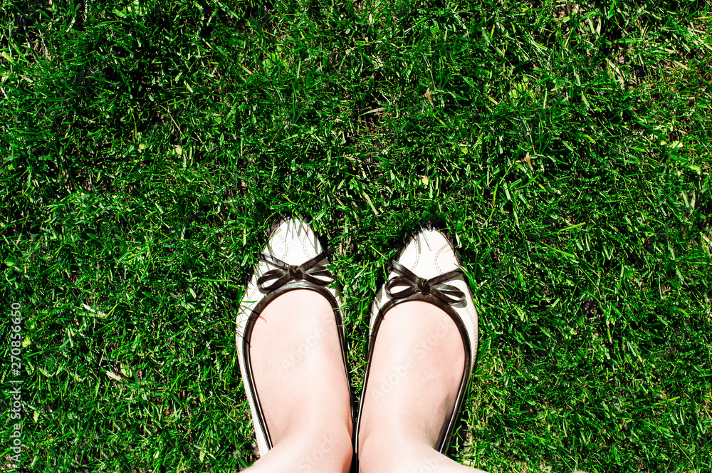 Top view of women's beige shoes that stand on the green cut grass